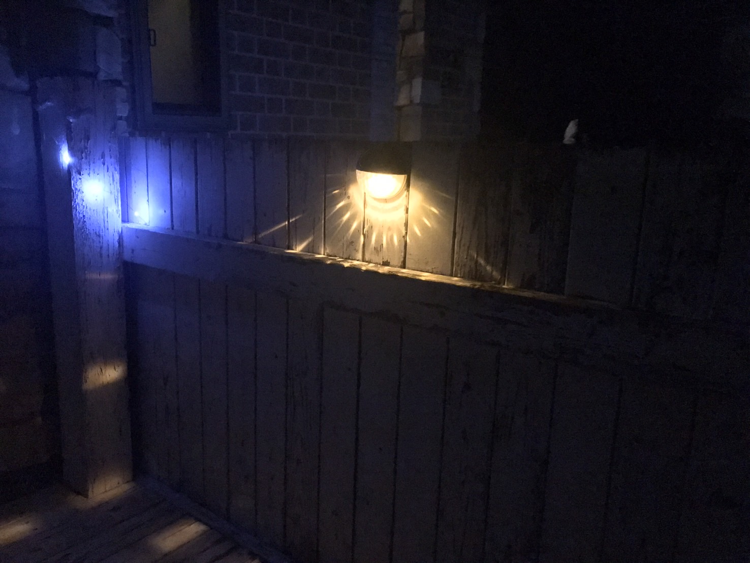 壁面に設置されたガーデンライトがやさしく照らすアンティーク調のウッドフェンス